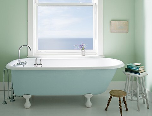 Une salle de bain verte sereine avec un bain sur pattes.